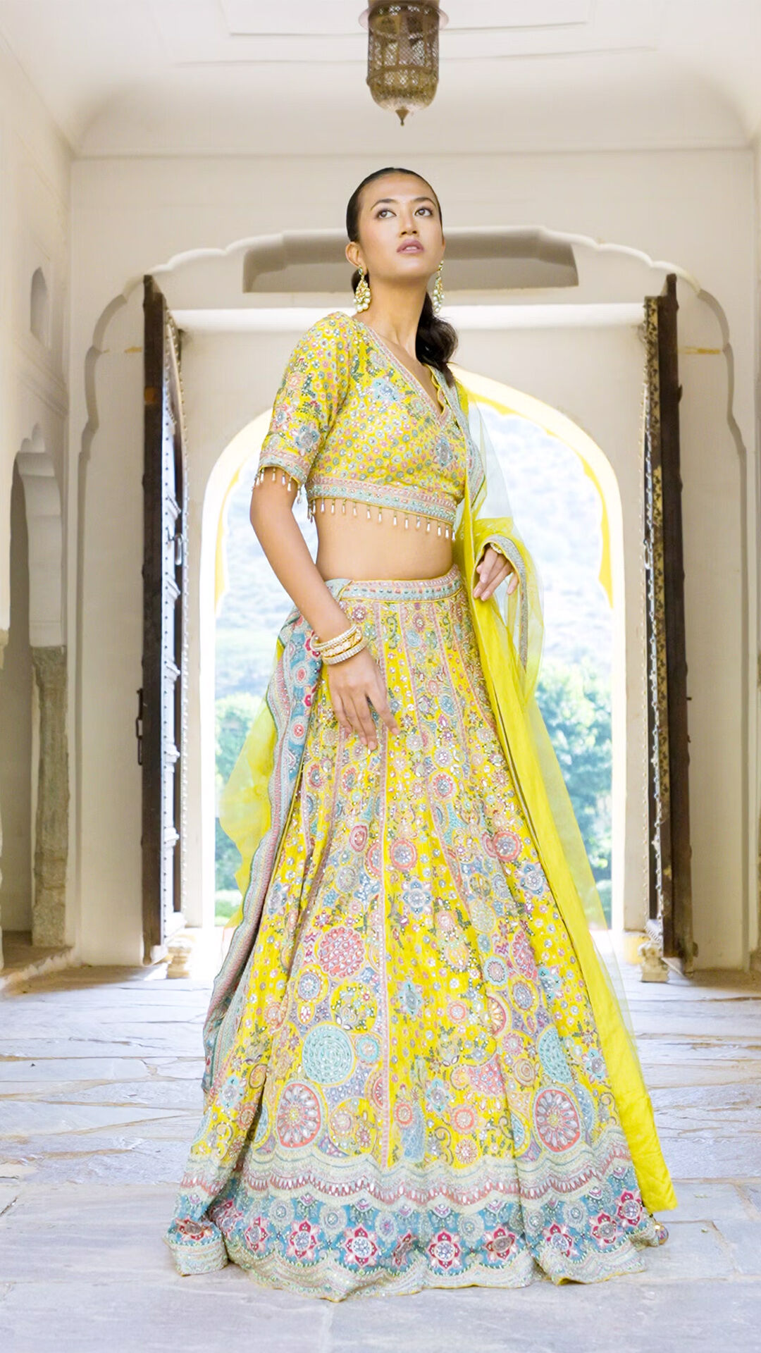 A woman wearing a conch shell yellow Indo-western set